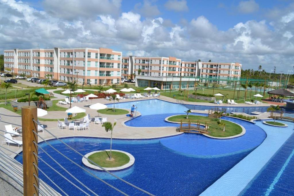a resort with a large pool with chairs and umbrellas at Muro Alto condomínio CLUBE AP 411 in Porto De Galinhas