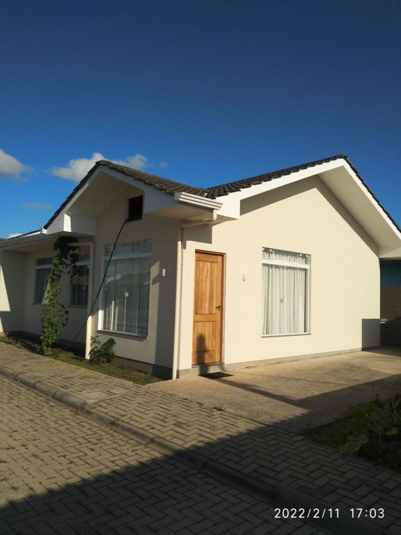 una casa blanca con una puerta en una calle en Cs6 Casa de 3 Quartos a 15min de Curitiba, en Campina Grande do Sul