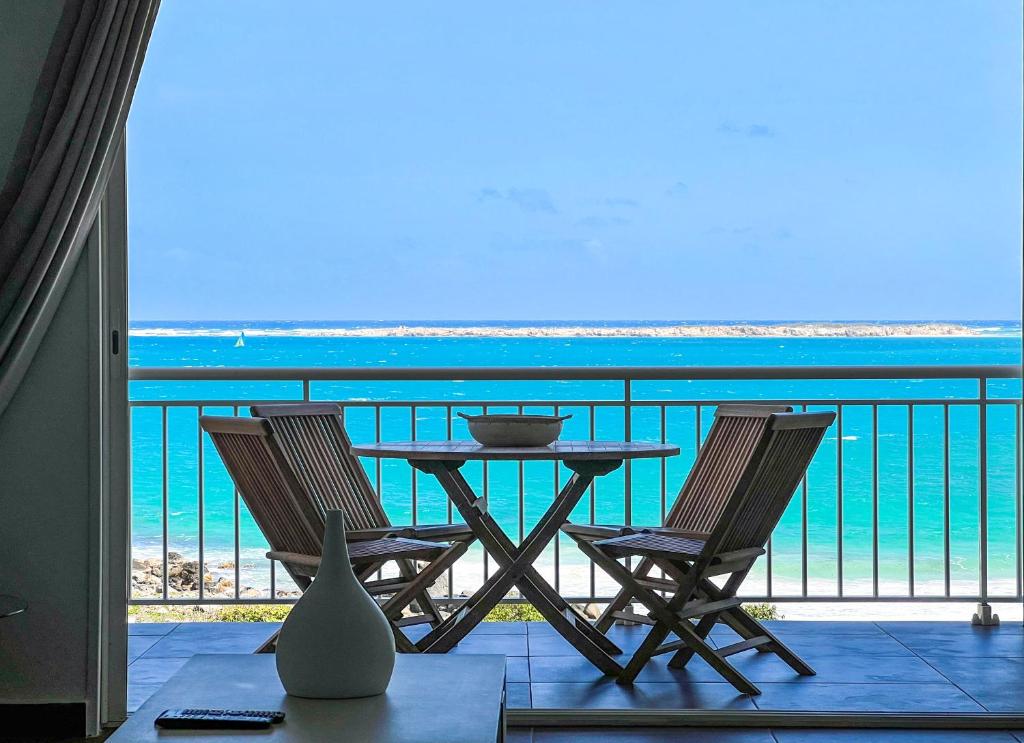 einen Tisch und Stühle auf einem Balkon mit Meerblick in der Unterkunft Front line unit 520 ft2 - 48 m2, on second floor, stunning ocean view in Saint Martin