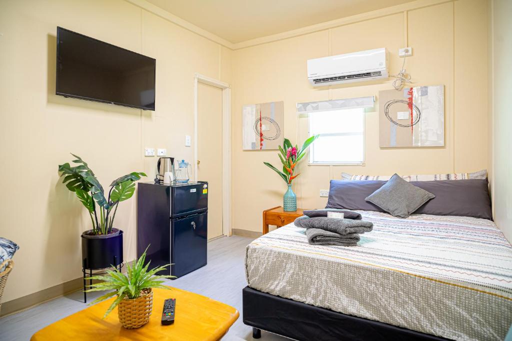 Green Hills Accommodation Village في بورت مورسبي: غرفة نوم مع سرير وتلفزيون على الحائط