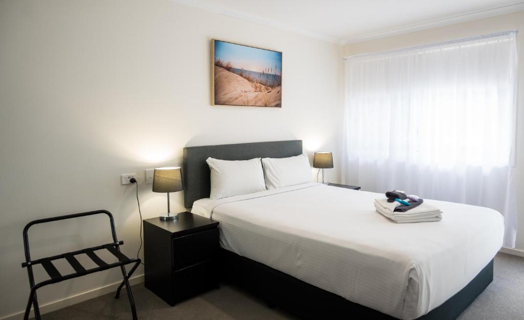 a bedroom with a large white bed and a chair at Petrie Mill Motel in Petrie