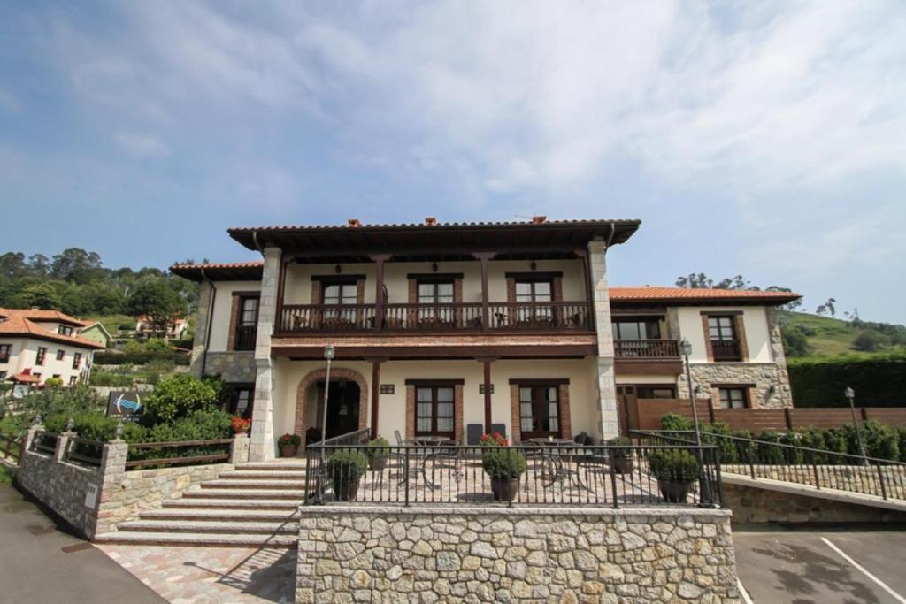 a large house with a balcony on top of a stone wall at Apartamentos Andrin in Andrín