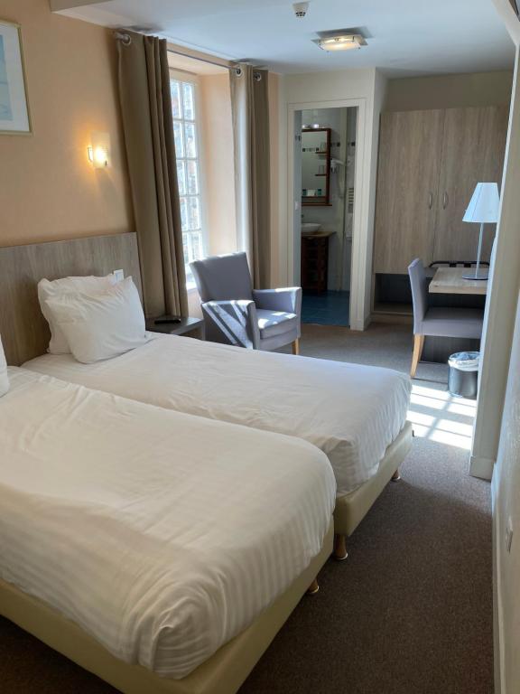 a hotel room with two beds and a desk at La Vieille Auberge in Le Mont Saint Michel