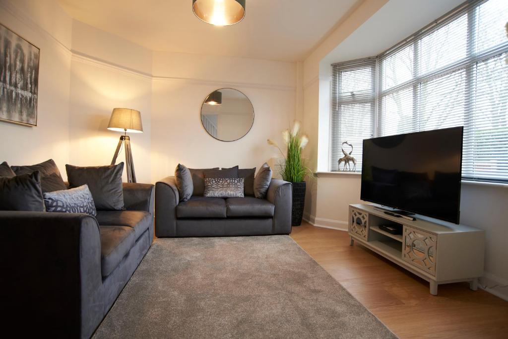 a living room with a couch and a flat screen tv at Doctors lane Stylish 3 Bedroom Family House with Parking in Melton Mowbray