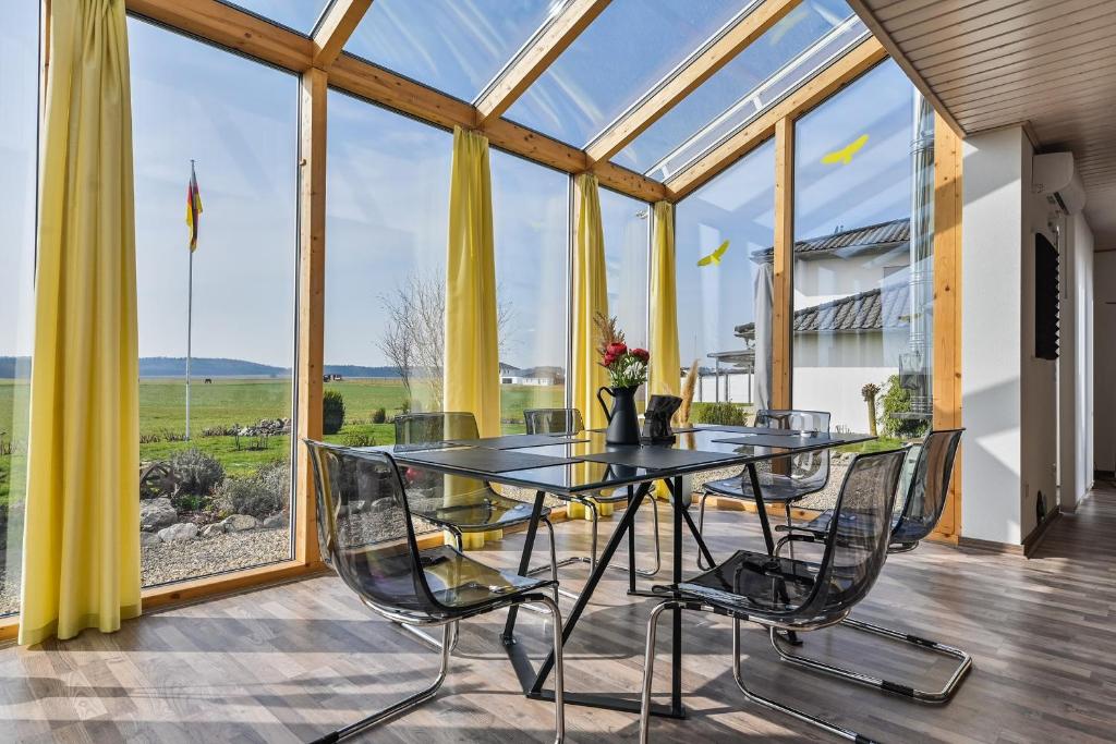 a glass dining room with a table and chairs at Ruhige Ferienwohnung mit Panoramablick in Ingoldingen