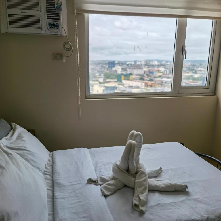 a stuffed animal is sitting on a bed in front of a window at Avida Davao Condos, downtown CM Recto Avenue, Davao City in Davao City