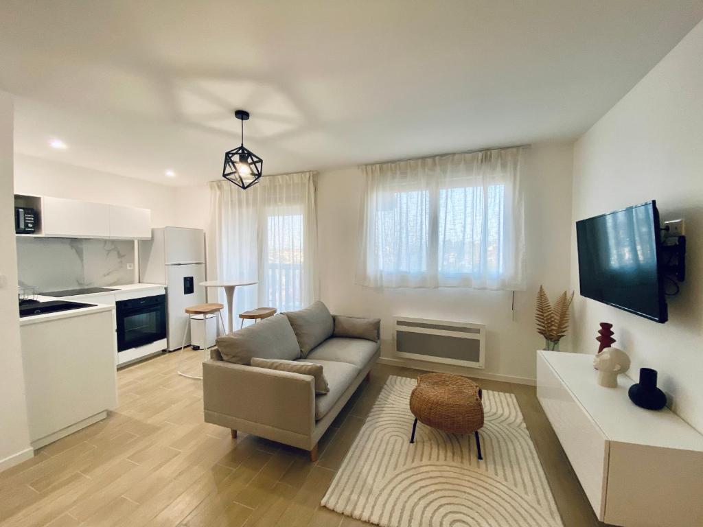 ein Wohnzimmer mit einem Sofa und einer Küche in der Unterkunft La ROSERAIE in Mont-de-Marsan