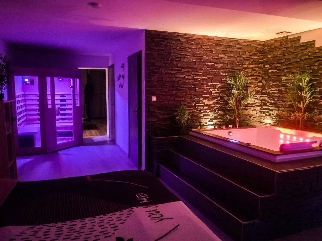 eine Badewanne mit violetten Lichtern in einem Zimmer in der Unterkunft Appart' spa privatif Gray in Gray