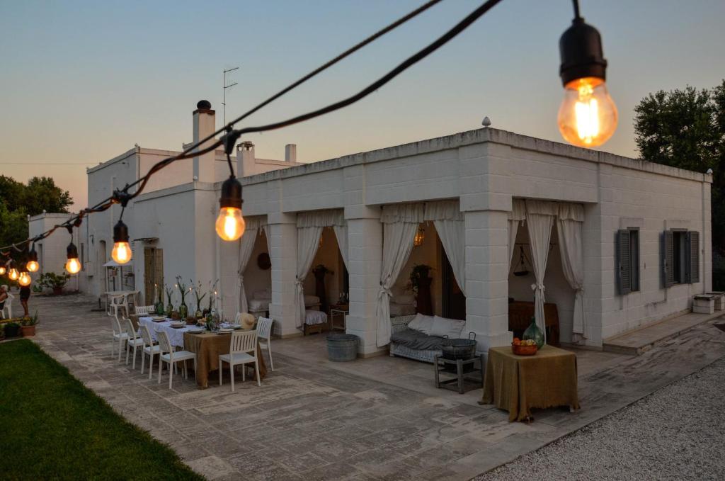 a white building with tables and chairs and lights at Cortebbianca in Fasano
