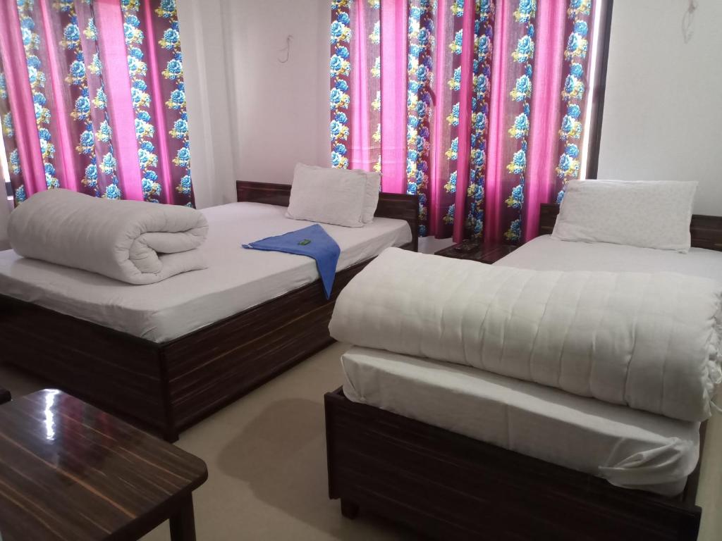 a room with two beds and a table and curtains at Hotel Kanthak in Lumbini