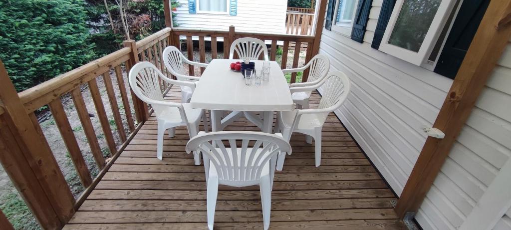 - une table et des chaises blanches sur une terrasse couverte dans l'établissement Mobil home 6 places, à La Roque-dʼAnthéron