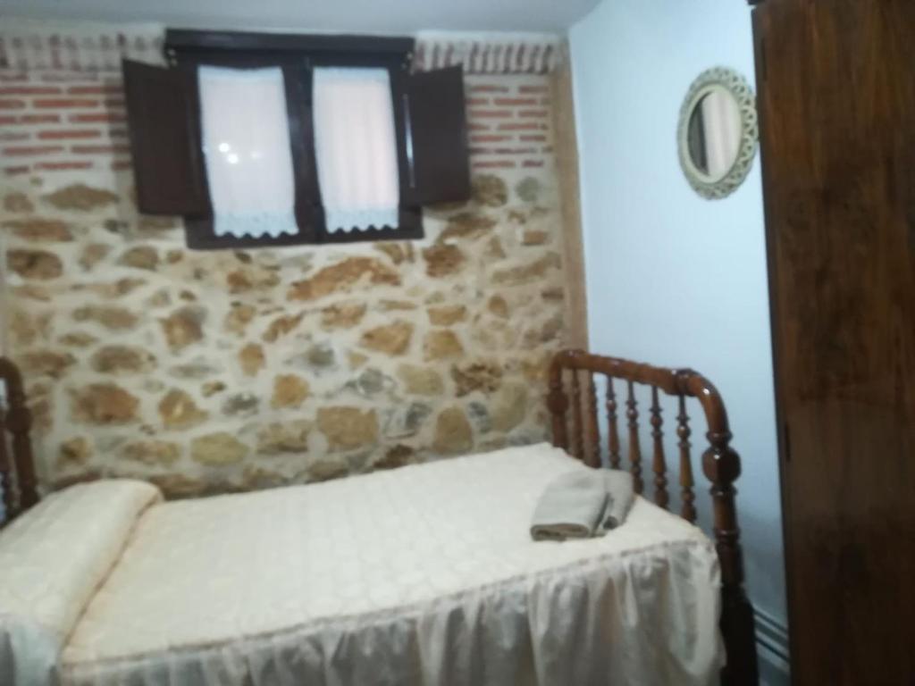 um quarto com uma cama e uma parede de pedra em La casita del herrador em El Burgo de Osma
