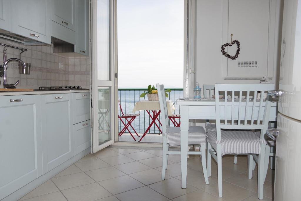 a kitchen with a white table and chairs and a balcony at Casa Colombo in Vietri sul Mare