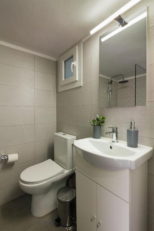 biała łazienka z toaletą i umywalką w obiekcie Sirens Athens Apartment w Atenach