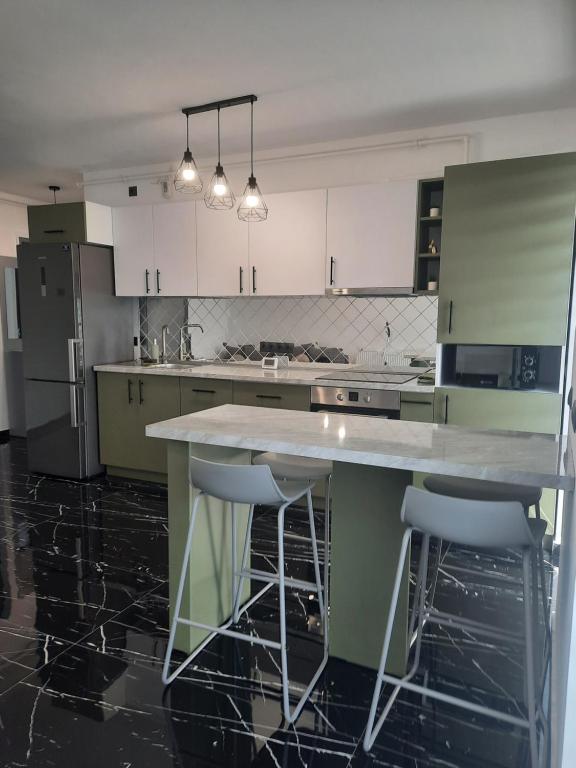 a kitchen with white cabinets and a island with bar stools at Apartament Coco in Baia Mare