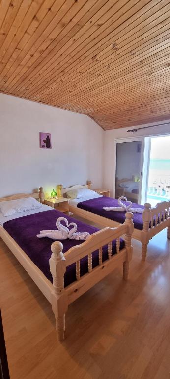 - une chambre avec 2 lits avec des draps violets et une fenêtre dans l'établissement Bradley apartmants HR, à Račišće
