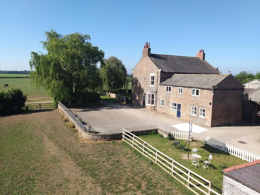 an old house with a white fence next to a field at Burton Grange Farmhouse Bed and Breakfast in Boroughbridge