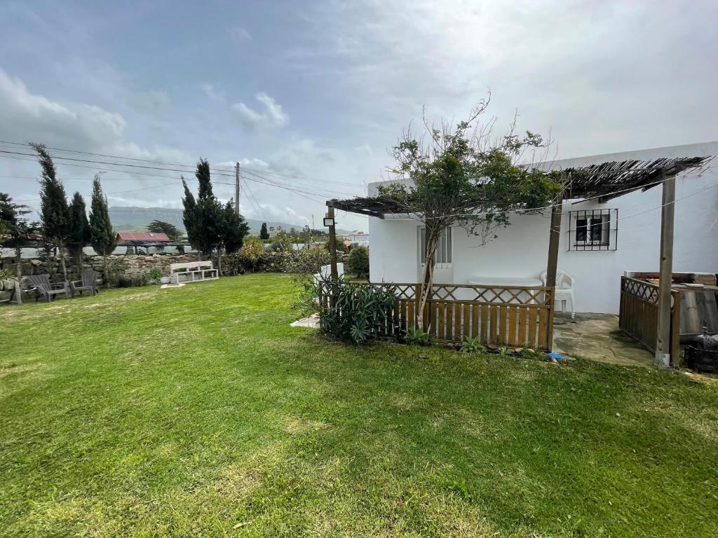 una pequeña casa blanca con un patio verde en Apartamento Antonia muy cerca de la playa, en Bolonia