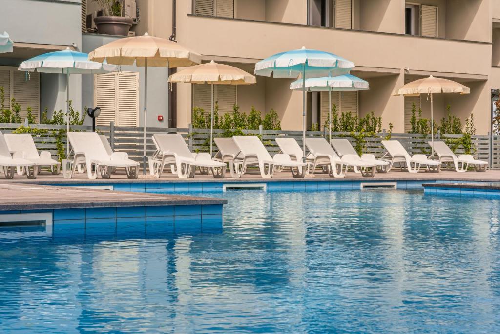 a swimming pool with chairs and umbrellas and a pool at Golden Hotel in Marina di Cecina