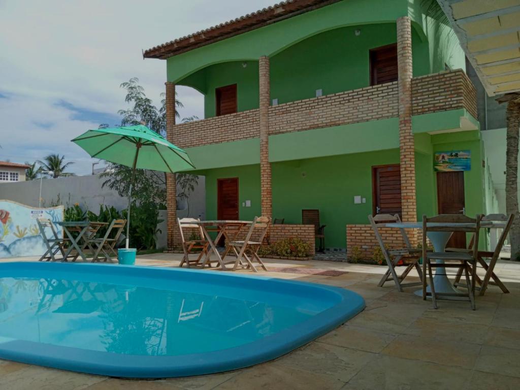 una casa con piscina, sedie e ombrellone di Chalé do Aldo a Canoa Quebrada