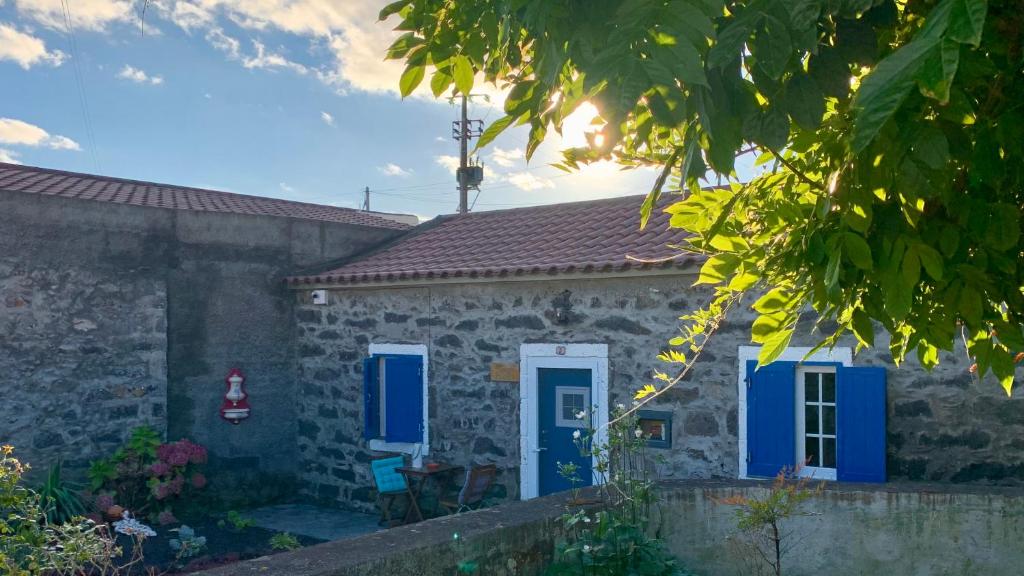 uma casa de pedra com portas azuis e um quintal em Casa do Priolo - Villaverde Azores em Feteiras