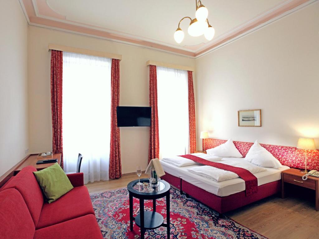 ウィーンにあるHPA Hotel Andreasのベッドと赤いソファが備わるホテルルームです。