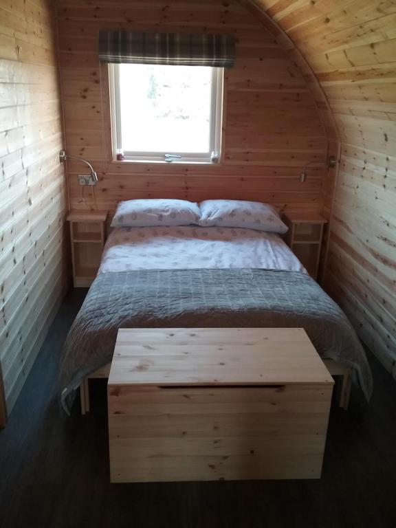 a bedroom with a bed in a wooden cabin at Heated Supersize Glamping Pod with ensuite bathroom, Wilburton, Nr Ely, Cambs in Wilburton