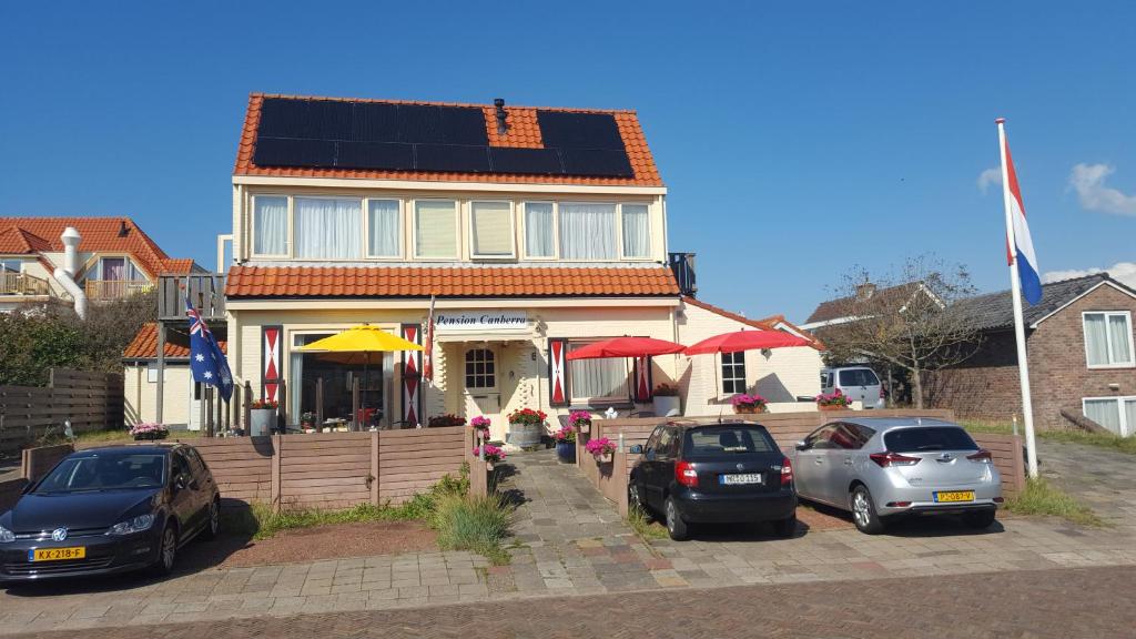 una casa con auto parcheggiate di fronte di pension canberra a Bergen aan Zee