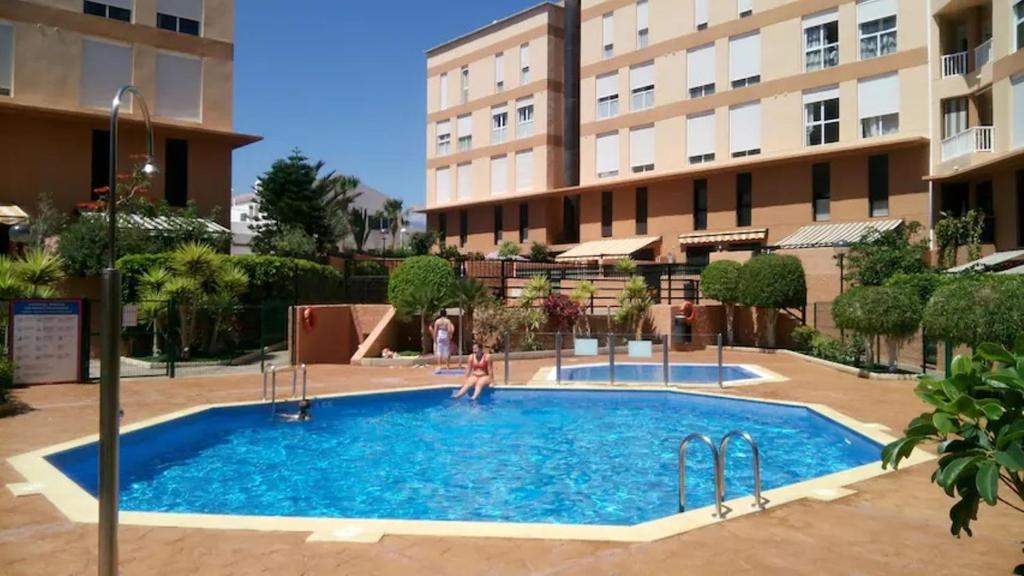 a woman standing in a swimming pool in front of a building at El Médano PlayaMar in El Médano