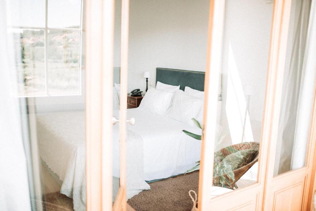 a bedroom with a bed with white sheets at Quinta do Paço Hotel in Vila Real