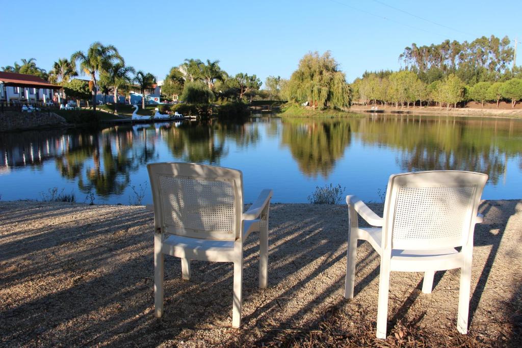 two white chairs sitting next to a lake at Herdade do Sardanito da Frente in Zambujeira do Mar