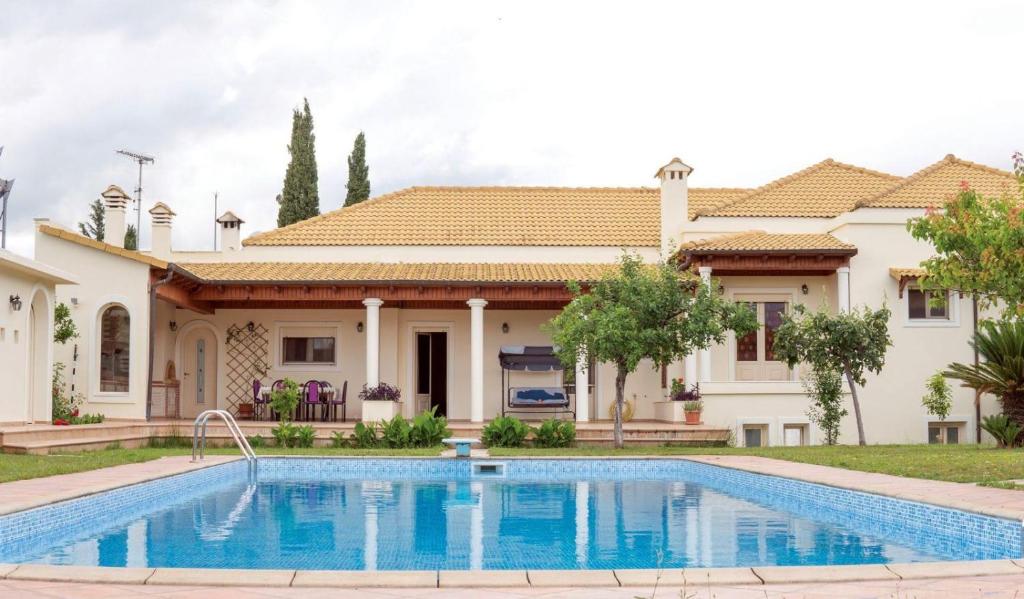 a villa with a swimming pool in front of a house at Laki Villa with pool and jacuzzi in Ágios Geórgios