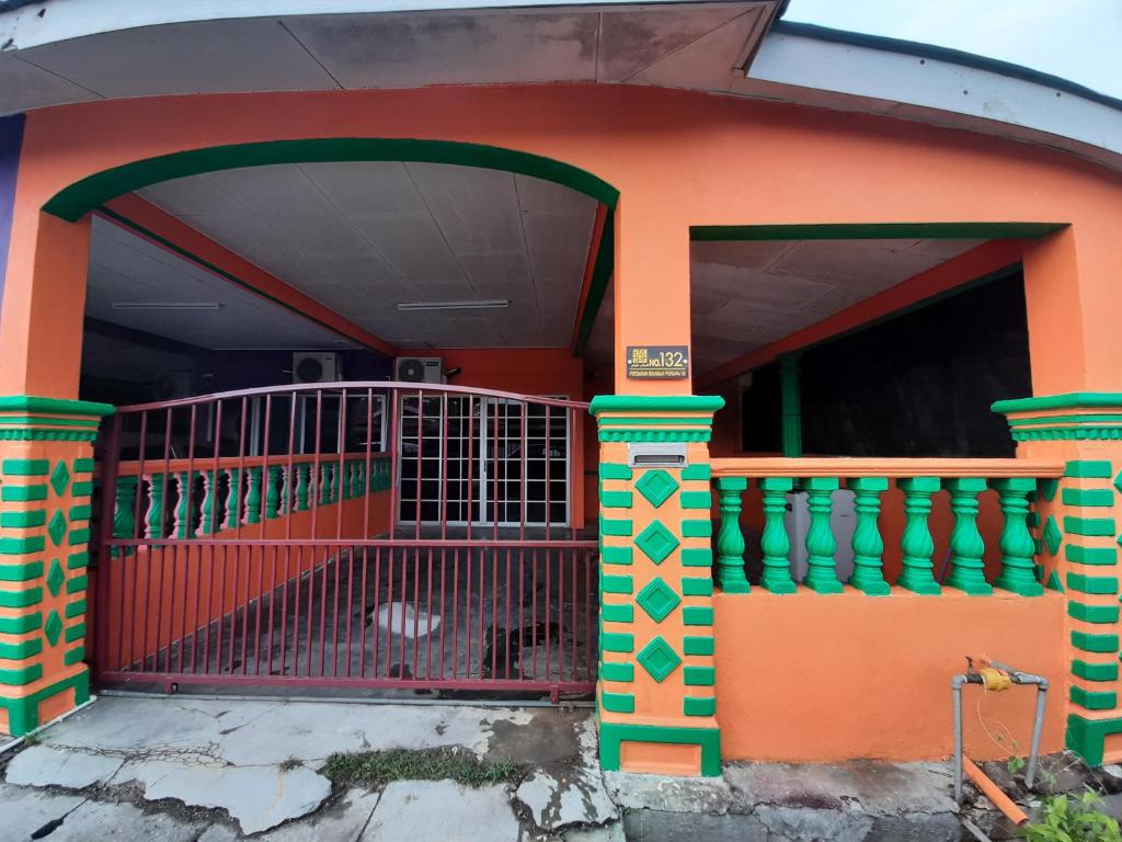 a orange and green house with a red gate at HAIDA'S HOMESTAY Seri Iskandar, Perak in Seri Iskandar