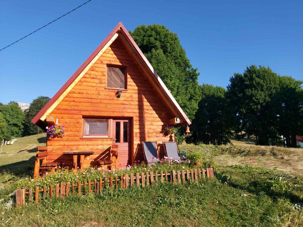 une petite maison en bois dans un champ avec une clôture dans l'établissement Nikitovic house, à Žabljak