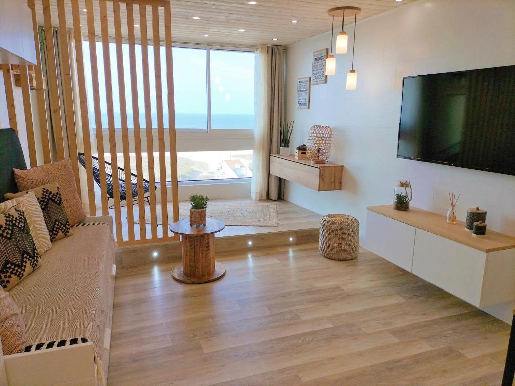 uma sala de estar com uma televisão grande e um sofá em Magnifique Studio Face Mer avec Place Privative. em Saint-Jean-de-Monts