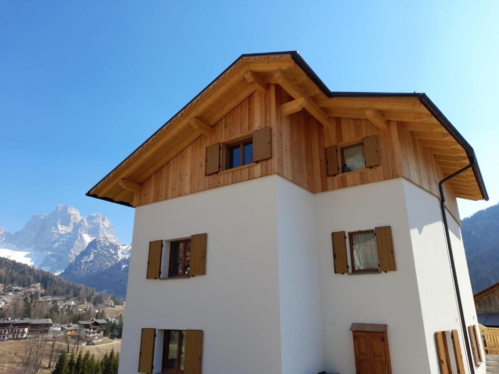 a building with a wooden roof with mountains in the background at Pelmo Mountain Lodge in Selva di Cadore