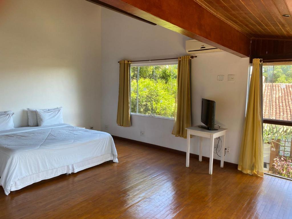 a bedroom with a bed and a television on a wooden floor at Departamento Dos reis in Búzios