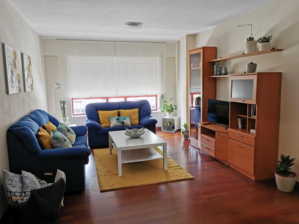 a living room with two blue chairs and a tv at Piso Bertamiráns in Amés