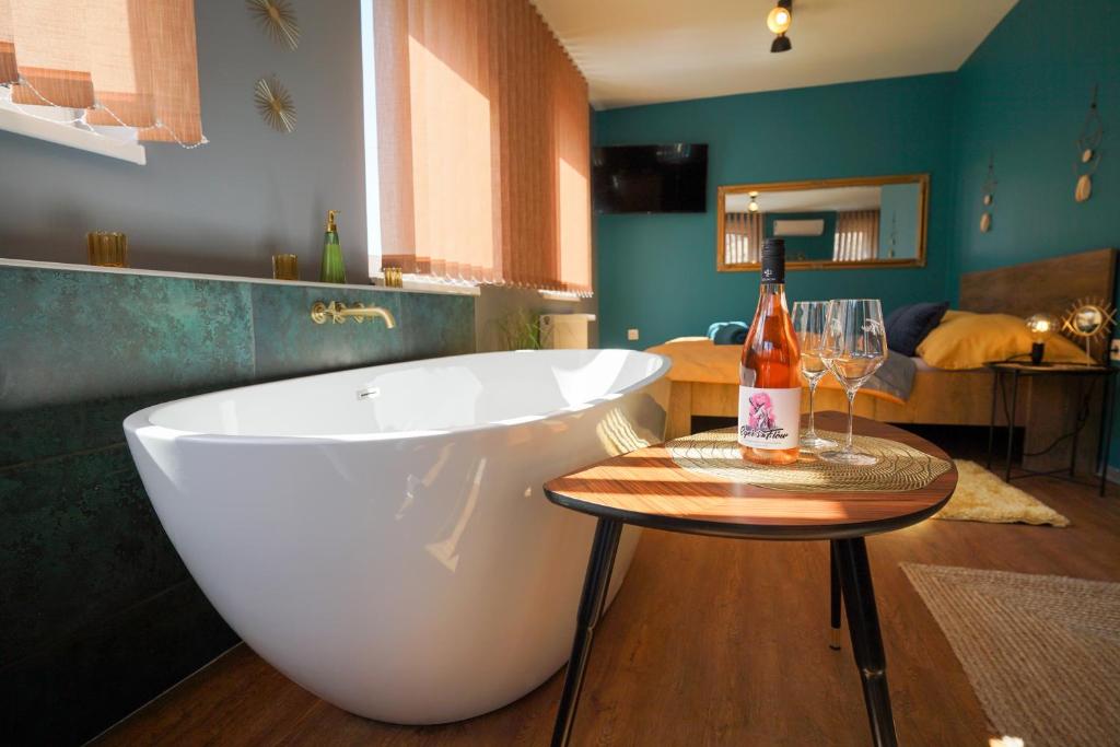 a bathroom with a tub and a table with a bottle of wine at Eger's Flow Apartment in Eger