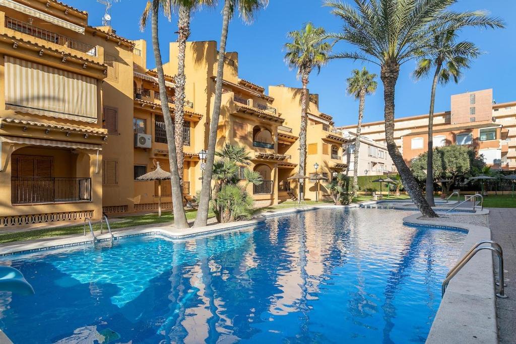 a swimming pool with palm trees and buildings at IDEAL para VERANO con PISCINA e INVIERNO con COCINA de LEÑA in La Mata