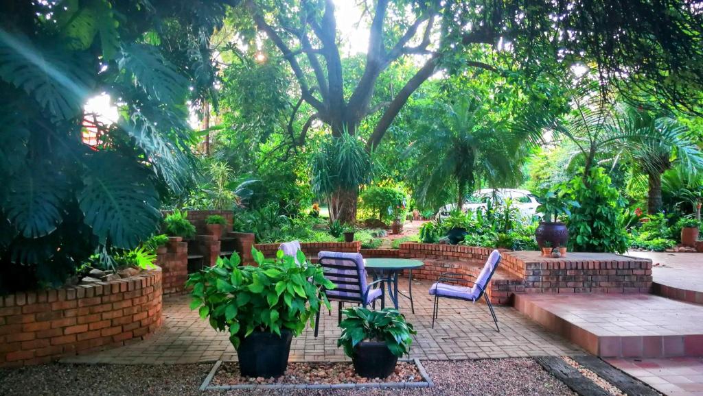 a patio with chairs and a table in a garden at Tree Aloe Guest House in Mokopane
