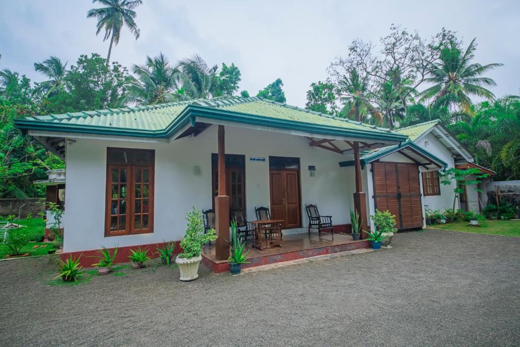 uma pequena casa branca com um telhado verde em The Esence of Sri Lanka em Ahungalla