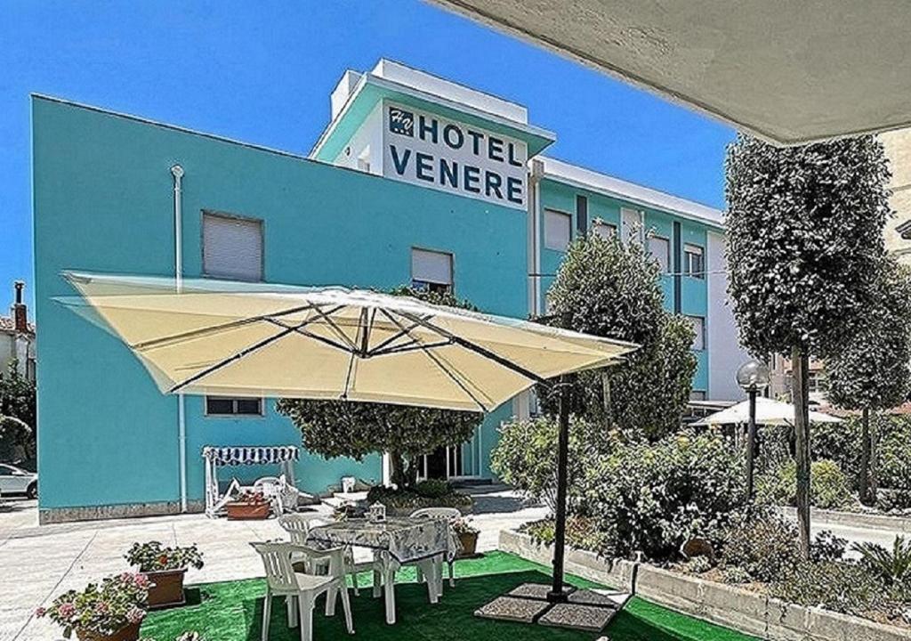 un edificio con una sombrilla delante de él en Hotel Venere, en Ascea