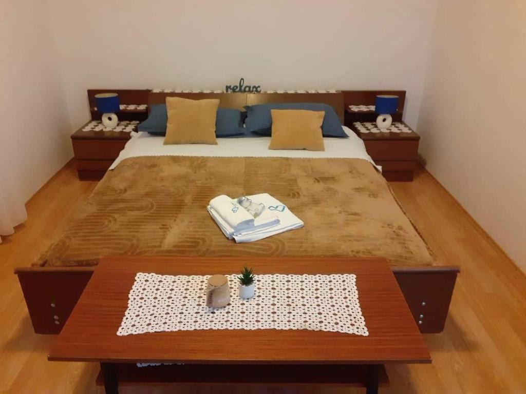 Schlafzimmer mit einem großen Bett und einem Holztisch in der Unterkunft Apartmani Brkljača 2 -Ive in Biograd na Moru