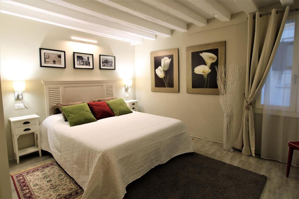 Schlafzimmer mit einem Bett mit grünen und roten Kissen in der Unterkunft San Marco Fenice 3bdr 2bth apartment in Venedig