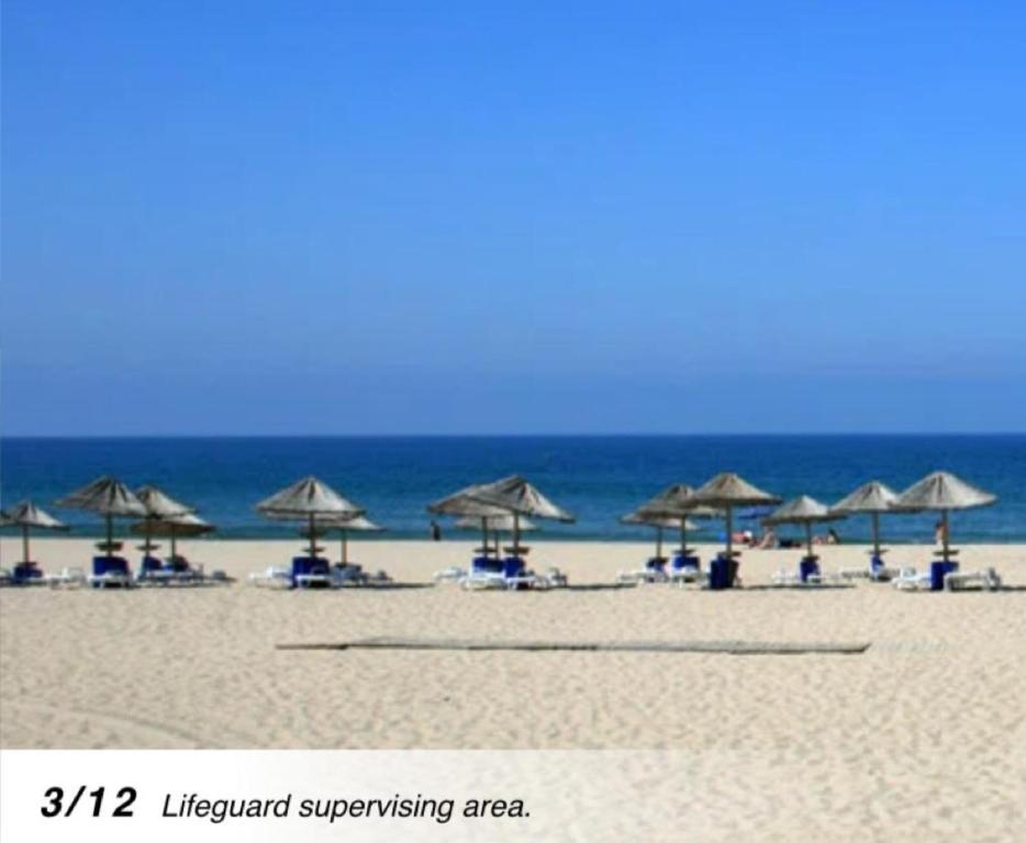 卡帕里卡海岸的住宿－Plage João de Caparica，海滩上设有遮阳伞和椅子,还有大海