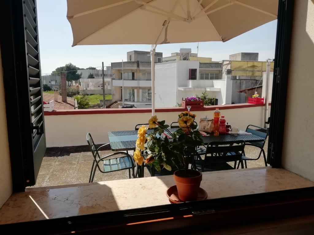 vistas a un balcón con mesa y sombrilla en Specchia Terrazza&Tavernetta Arcobaleno, en Specchia