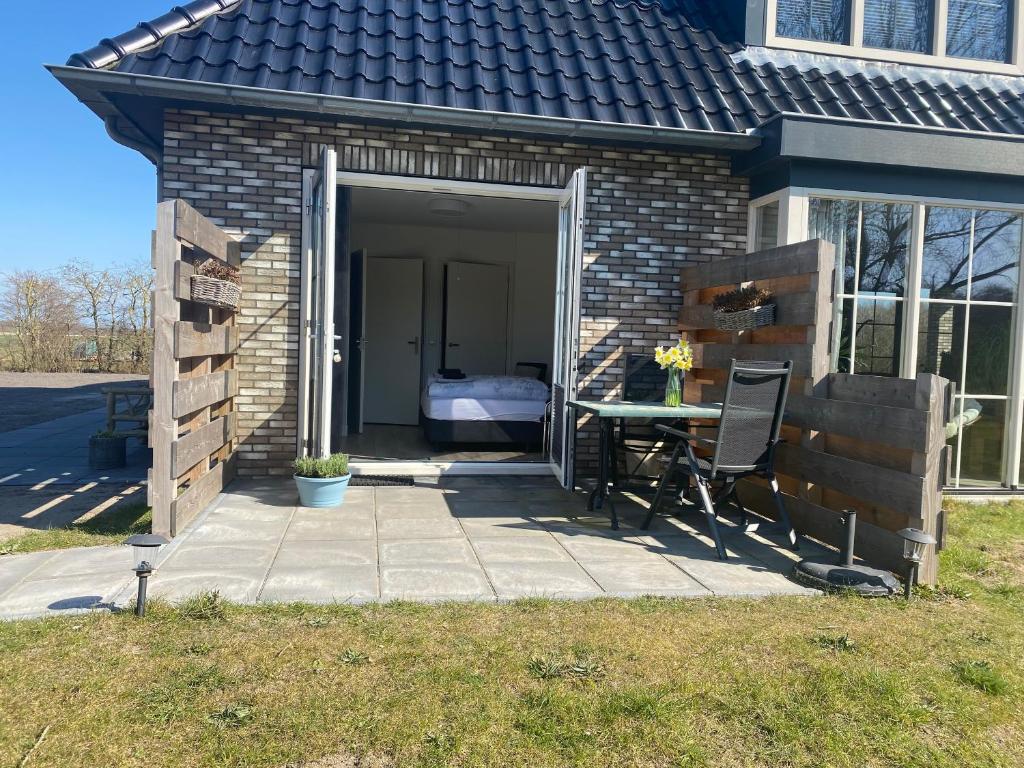 a patio with a table and chairs in front of a building at Logies Boszicht Texel in De Koog