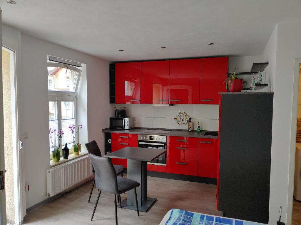 een keuken met rode kasten en een tafel en stoelen bij Bei Charlotte in Sonneberg