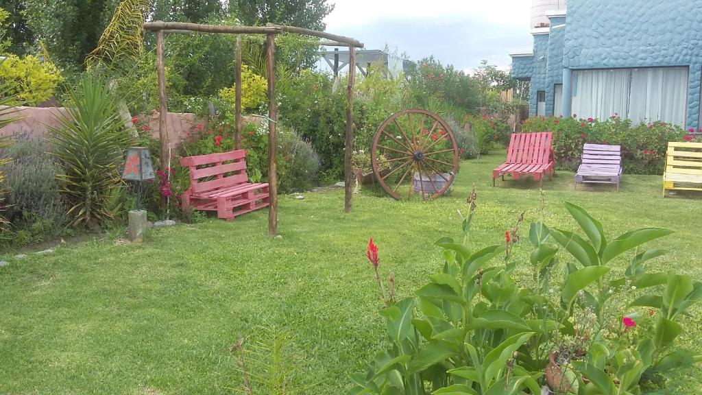 un patio con 2 sillas rojas y un cenador de madera en Cabañas Cafayate II en Cafayate